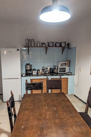 A compact kitchen with a dining table, chairs, a refrigerator, a microwave, and a coffee maker. - Finca Luz de Palmera by Interhome (Santa Lucia de Tirajana)