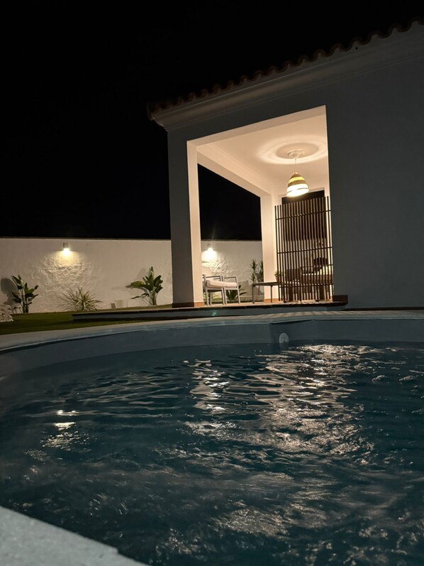 A swimming pool with a patio area, a lamp, and a fence.