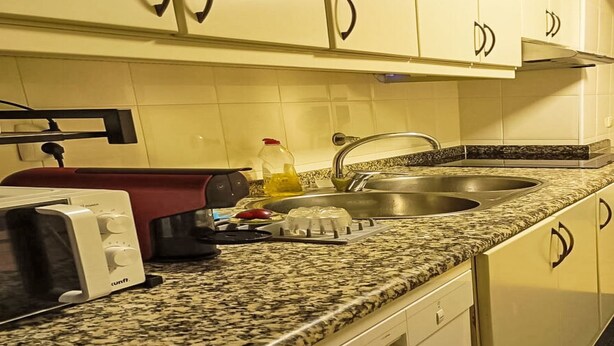 Uma cozinha com bancada de granito, torradeira, chaleira e pia.