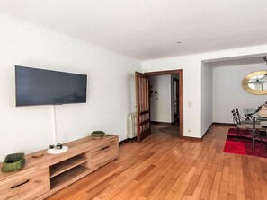 A modern living room with a flat-screen TV, wooden entertainment unit, and a dining area with a red rug. - Oceanview First Line with 2 Pools 6 by Interhome (Ovar / Praia de Esmoriz)