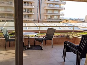 A balcony with a table and chairs, overlooking a residential area with multiple-story buildings and a clear view of the sea. - Oceanview First Line with 2 Pools 6 by Interhome (Ovar / Praia de Esmoriz)