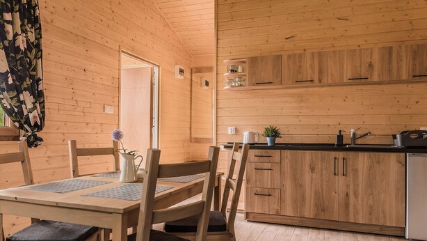 Un interior de madera con una mesa de comedor, sillas, una zona de cocina y un techo de madera.