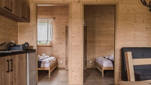 Una cabaña con dos camas de madera, un kitchenette y una ventana con cortinas.