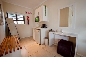 A compact kitchen with a refrigerator, sink, and a small countertop. - Interlaken Guest House (Wilderness)