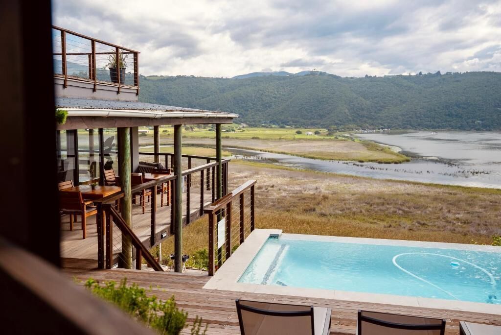 A poolside area with a view of a river and hills.