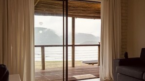 Ein Zimmer mit einer Schiebetür zu einem Balkon mit Blick auf das Meer und die Hügel.