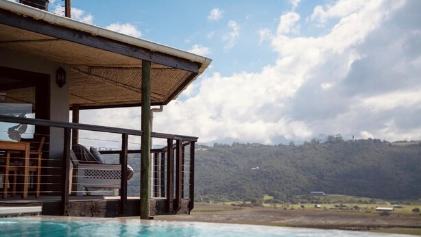 Ein Poolbereich mit überdachter Lounge und Blick auf eine hügelige Landschaft.