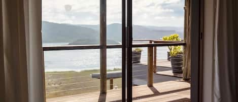Una terraza de madera con vistas a un cuerpo de agua y montañas.