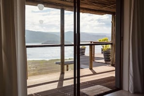 A wooden deck with a view of a body of water and mountains.