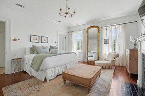 A bedroom with a large bed, a sitting area, a mirror, and a fireplace. - Luxury Historic Mansion Overlooking Madison Square by Lucky Savannah (Savannah)