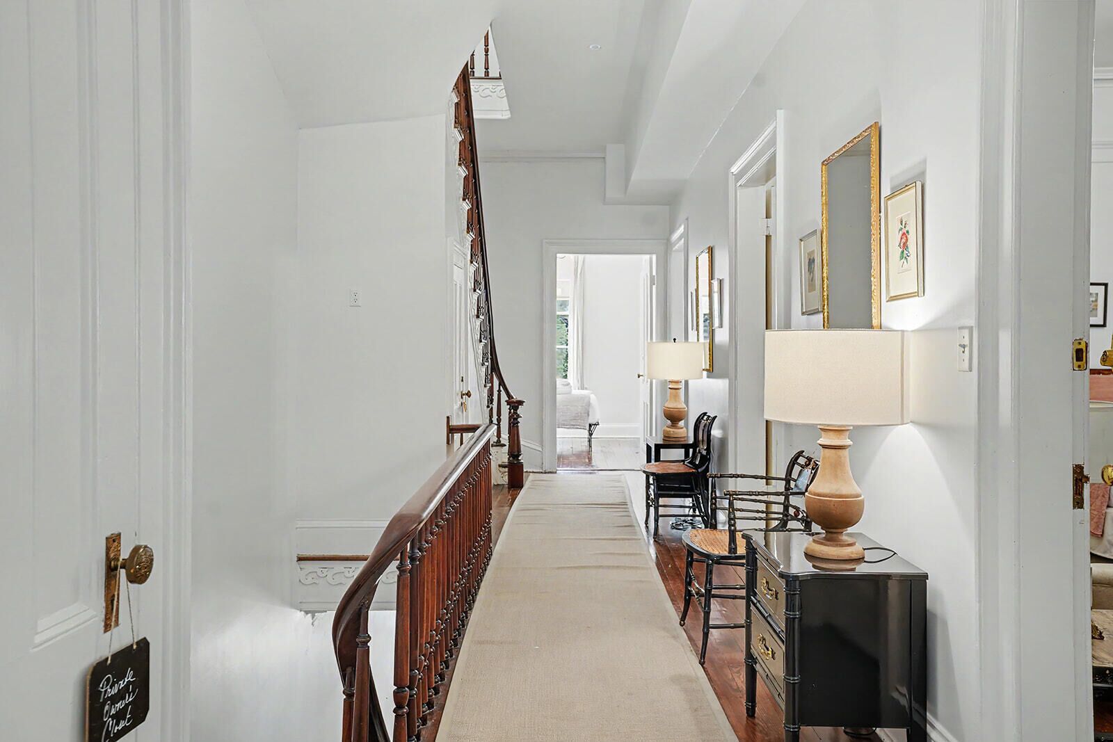 A hallway with a wooden staircase, a sofa, a lamp, and a cabinet.