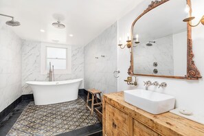 Un baño moderno con una bañera independiente, un tocador con lavabo y un espejo grande.