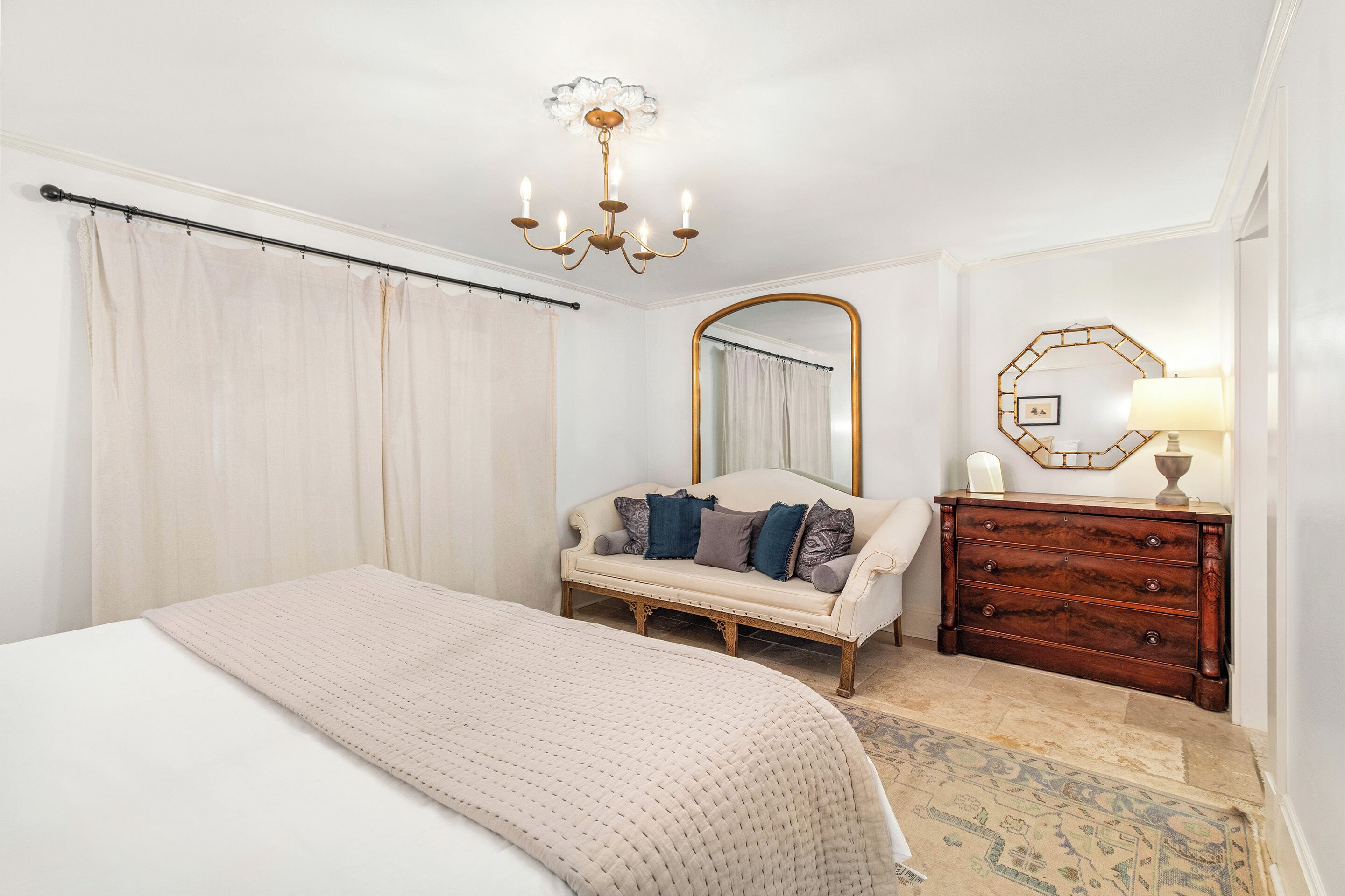 Une chambre à coucher comprenant un lit, un canapé, une commode, un miroir et un lustre.