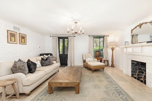 Ein Wohnzimmer mit Sofa, Sessel, Couchtisch, Kamin und einer Chandelier.