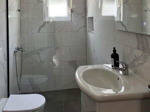 Ein Badezimmer mit Toilette, Waschbecken, Spiegel und Dusche.