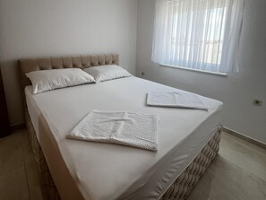 Ein ordentlich bezogenes Bett mit Kopfteil, zwei Kissen und zwei gefalteten Decken.