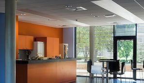 A modern kitchen with a central island, built-in appliances, and a dining area with chairs and a table. - Adonis Dijon Single Apartment (Dijon)