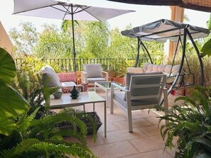 Eine Terrasse im Freien mit einer Schaukel, einem Tisch und einer gepolsterten Bank.