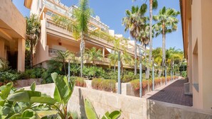 A multi-story hotel with balconies, palm trees, and a paved walkway. - Real1b - Beautiful apt With Tropical Terrace (Marbella)