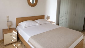 Un dormitorio con una cama de madera, una mesita de noche con una lámpara, un armario y un espejo en la pared.