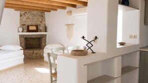 Una cocina rústica con vigas de madera a la vista, chimenea de piedra y encimera blanca.