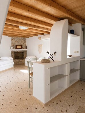 A rustic kitchen with exposed wooden beams, a stone fireplace, and a white countertop. - Paros Casa Prive - Deluxe Shared Pool Nest (Ag Charalambos)
