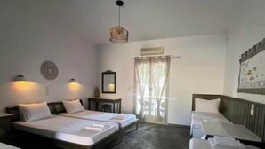 Habitación de hotel con dos camas, un escritorio, una silla, una lámpara colgante y un ventanal con cortinas.