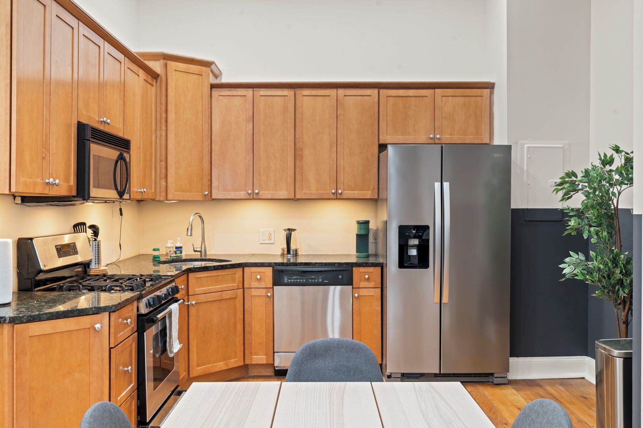 Una cocina moderna con armarios de madera, electrodomésticos de acero inoxidable, lavavajillas y cafetera.