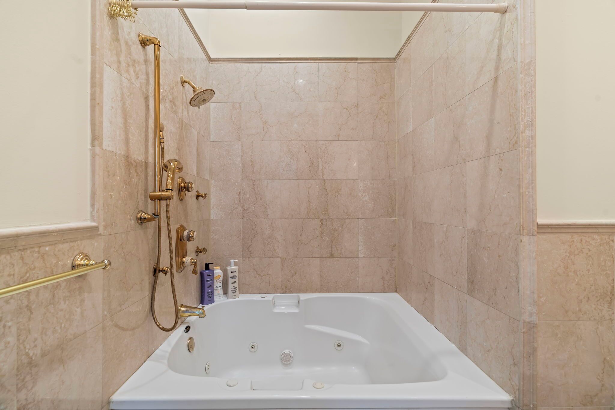 A bathroom with a bathtub, shower, and marble walls.