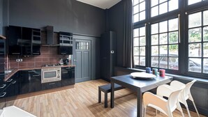 Eine moderne Küche mit dunklen Schränken, einer eingebauten Mikrowelle und einem Essbereich mit Tisch und Stühlen.