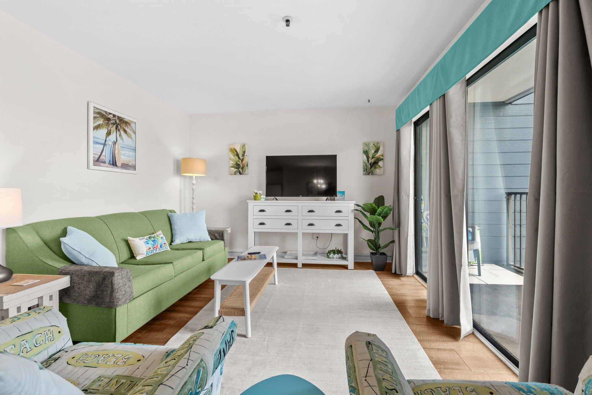 Een woonkamer met een groene bank, een witte salontafel en een flatscreentelevisie.