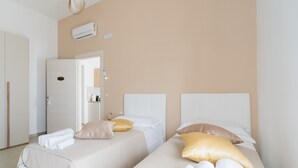 Una camera d'albergo con due letti, pareti color beige e un condizionatore d'aria.