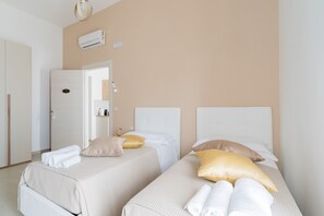 Une chambre d’hôtel avec deux lits, des murs de couleur beige et un appareil de climatisation.