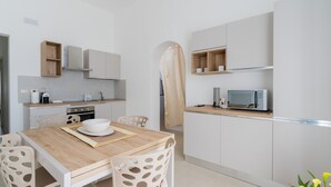 Una cucina moderna con mobili bianchi, un tavolo da pranzo in legno e un forno a microonde.