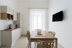 A modern kitchen with a microwave, wooden cabinets, and a dining table with chairs. - Bed and Breakfast 'Camera Jacky' with Balcony, Wi-Fi and Air Conditioning (Galatone)
