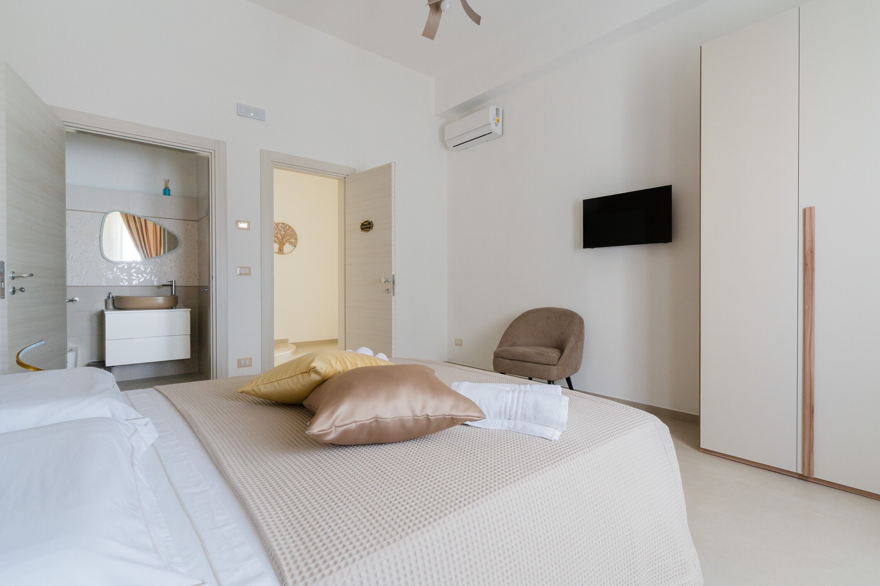 Quarto com cama, cadeira, televisão e guarda-roupa.