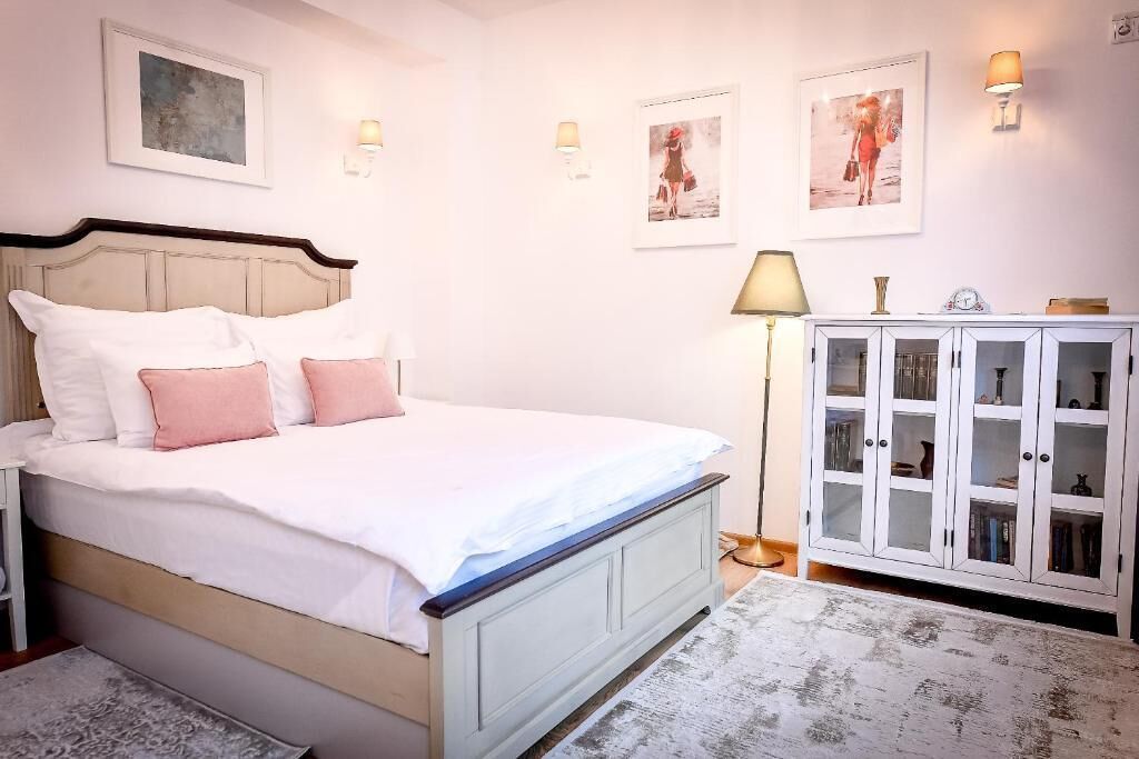 A bedroom with a bed, bedside tables, a cabinet, and wall-mounted lamps.