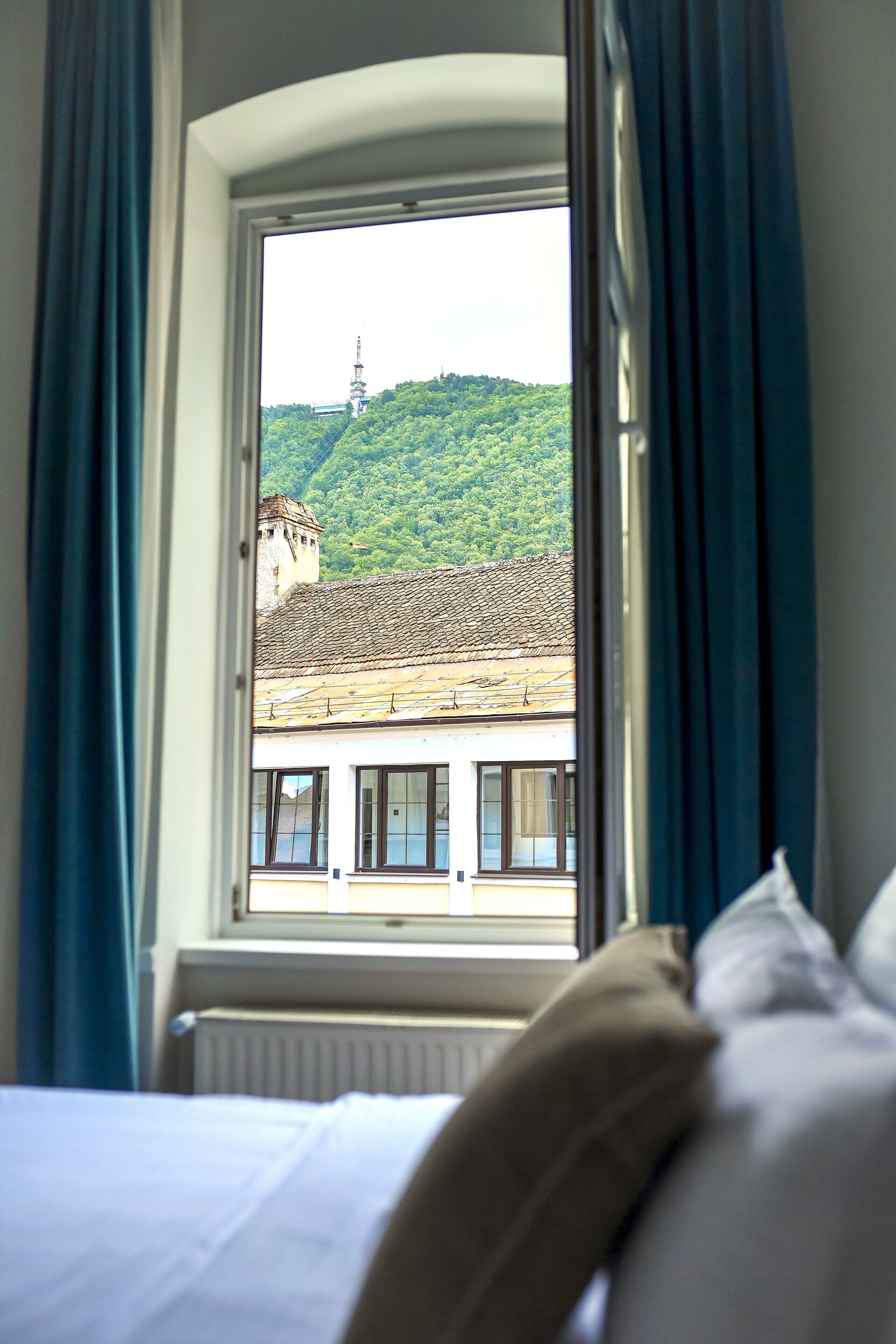A hotel room with a bed, a window, and a view of a building with a tower.