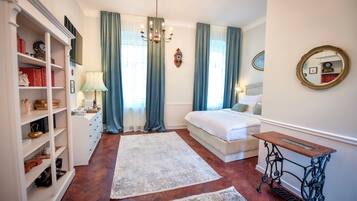 A bedroom with a bed, a sewing machine, a bookshelf, and a large window with curtains.