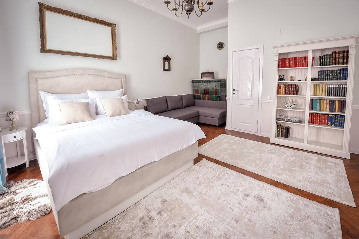 A bedroom with a bed, a nightstand, a bookshelf, and a mirror.