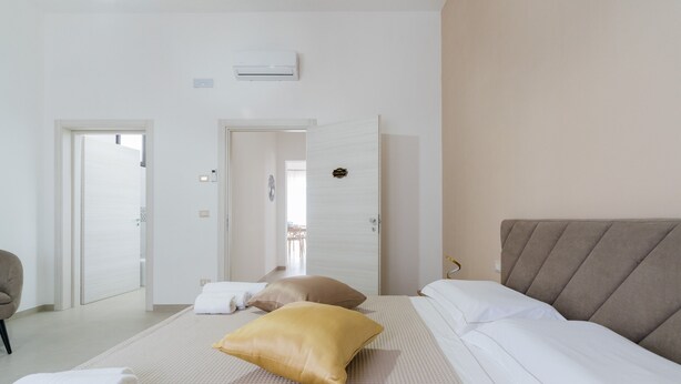 Una habitación de hotel con una cama, una silla y una puerta que da a otra habitación.