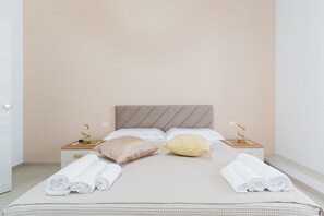 Een hotelkamer met een bed, twee nachtkastjes, een hoofdbord en opgerolde handdoeken op het bed.