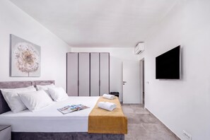 Habitación de hotel moderna con una cama, una mesita de noche con una revista, un televisor y un armario.