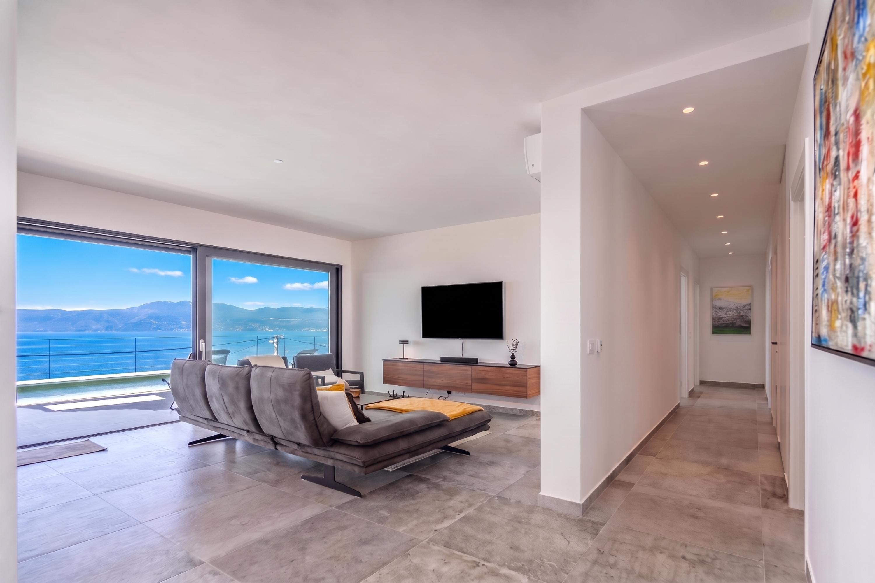 A modern living room with a large window, a flat-screen TV, and a minimalist design.