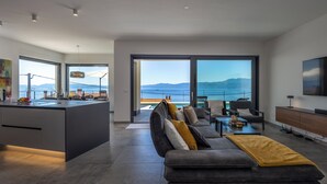 Een moderne woonkamer met een bank, bijzettafeltje en uitzicht op zee.