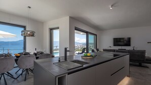 Een moderne keuken met een groot schiereiland, een eethoek en uitzicht op zee.