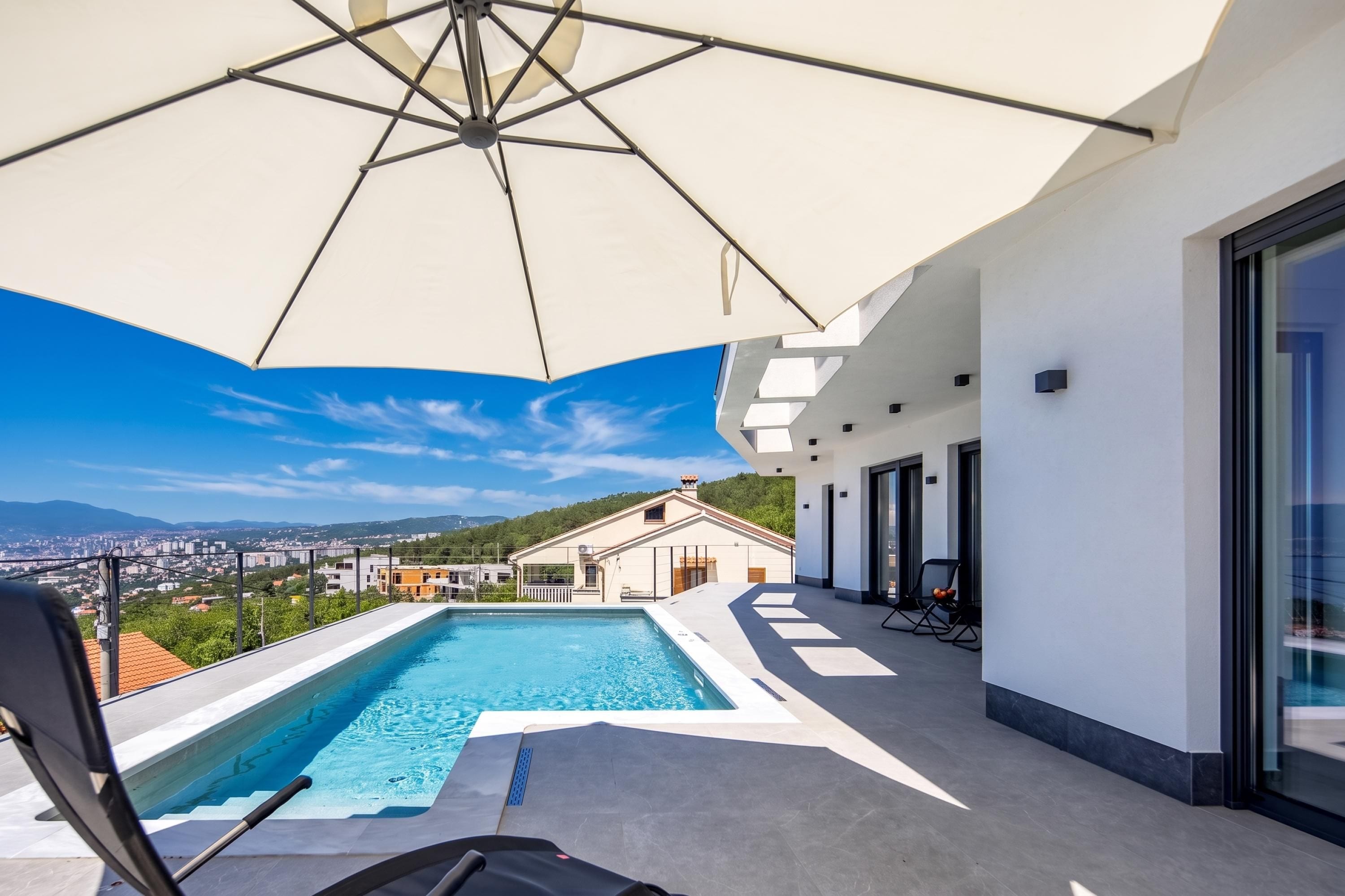 A rooftop swimming pool with a clear view of the cityscape and mountains in the background.