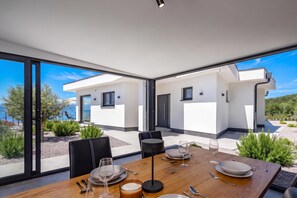 Un comedor moderno con una mesa preparada para dos, ventanas amplias y vistas al paisaje circundante.