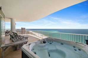A balcony with a hot tub, lounge chairs, and a view of the ocean. - Turquoise Place 2401C by Liquid Life (Orange Beach)