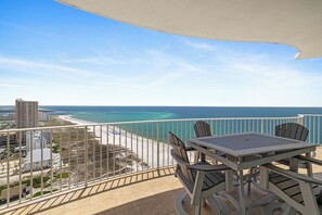 A balcony with a view of the beach and ocean, a table, and chairs. - Turquoise Place 2401C by Liquid Life (Orange Beach)